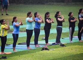 New Delhi, India, June 18 2022 - Group Yoga exercise class Surya Namaskar for people of different age in Lodhi Garden, International Yoga Day, Big group of adults attending a yoga class in park photo