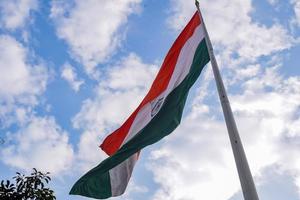 India flag flying high at Connaught Place with pride in blue sky, India flag fluttering, Indian Flag on Independence Day and Republic Day of India, tilt up shot, Waving Indian flag, Har Ghar Tiranga photo