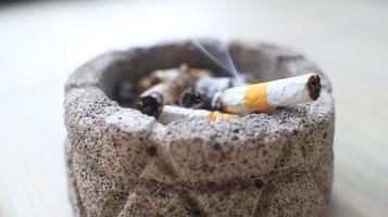 Cigarette in ashtray on a wooden table. Close up. photo