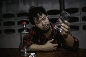 Asian man drink vodka alone at home on night time,Thailand people,Stress man drunk concept photo