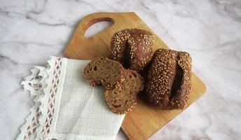 a small dark bun with sesame seeds and seeds is cut on a board with a knife and a napkin photo