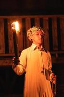 An Arabian man holding a fire torch in the front of a wooden house photo