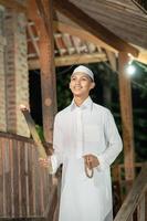 Handsome Islamic man with white Muslim dress in the dark night photo