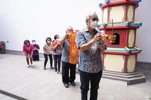 Bandung City, Indonesia, 2022 - Buddhist People pray together with the monks while giving the offering in front of the altar photo