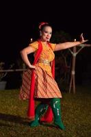 Balinese dancer with an orange costume and wearing makeup posing like a dancer while in black hair photo