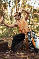 Dancing pose from a scary Balinese man with a golden necklace and crown on her body shirtless photo