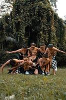 un grupo de indonesios bailando posan con un traje dorado mientras usan maquillaje en la hierba verde foto