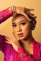 beautiful Balinese woman wearing makeup in a pink dress while posing with exotic hands photo