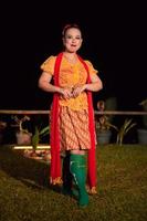 mujer indonesia con un hermoso vestido batik naranja con una bufanda roja y labios rojos en la cara foto