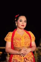 Sundanese woman wearing a short dress and traditional yellow dress with red scarf and makeup after the dance performance photo