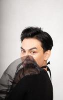 Asian man poses in a black costume while wearing makeup and black hair photo