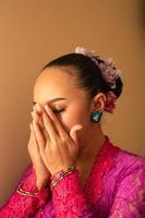 Balinese woman wearing a pink dress during the praying process in the temple photo