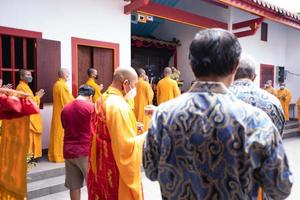 Bandung City, Indonesia, 2022 - Buddhist People pray together with the monks while giving the offering in front of the altar photo