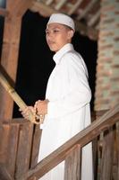 A Muslim man standing on the stairs in front of the traditional house photo