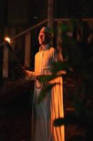 A Muslim man standing with the fire torch in her hand at the front of the village photo