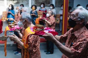 Bandung City, Indonesia, 2022 - The congregation and the monks standing together while praying at the altar to respect the god photo
