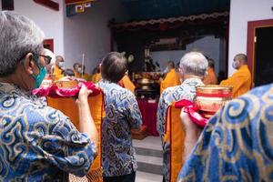 Bandung City, Indonesia, 2022 - Buddhist People pray together with the monks while giving the offering in front of the altar photo