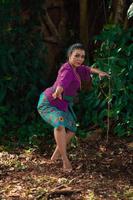 Sexy Sundanese woman with purple dress dancing in front of the big tree and the green leaves in the background photo