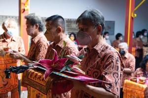 Bandung City, Indonesia, 2022 - The congregation and the monks standing together while praying at the altar to respect the god photo