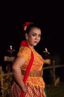 An Asian Traditional dancer in an orange dress with a red scarf and makeup performing at the dance festival photo