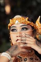 Beautiful Indian bride wearing a golden crown and a golden necklace with tattoos on her hands photo