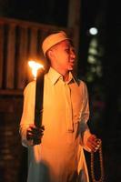 A Muslim man holding a fire torch at the campsite in the village photo