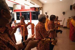 Bandung City, Indonesia, 2022 - the old man brings the offerings to the altar while praying with the monks photo