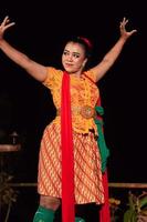 una bailarina tradicional asiática con un vestido naranja con una bufanda roja y maquillaje actuando en el festival de danza foto