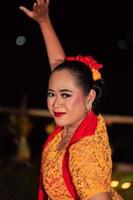 Close-up face of a Balinese woman during the traditional dance performance while wearing an orange costume and makeup photo