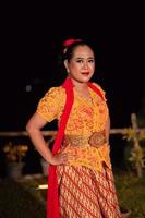Beautiful Indonesian women wearing an orange traditional dance costume called kebaya when dancing a danced called jaipong photo