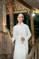 A Muslim man standing on the stairs in front of the traditional house photo