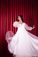 Asian woman poses in a Glamor wedding dress with flying fabric from the dress photo