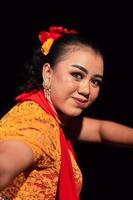 Beautiful face of an Indonesian woman in makeup while dancing a traditional dance in an orange costume during the festival photo