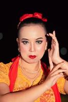 Exotic Javanese woman wearing beautiful makeup with red lips while wearing a traditional yellow costume and red scarf photo