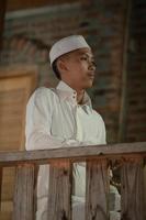 A Muslim man standing on the balcony of a wooden house in the village photo