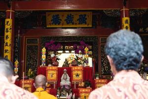 Bandung City, Indonesia, 2022 - The congregation and the monks standing together while praying at the altar to respect the god photo