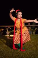 Balinese dancer with an orange costume and wearing makeup posing like a dancer while in black hair photo