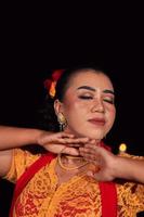 cara cercana de una mujer indonesia con maquillaje y un vestido naranja mientras usa una pieza de joyería de oro en el cuello foto