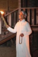 An Islamic man wearing a Muslim dress in the dark night with the fire torch lighting photo