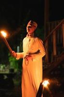 A Muslim man standing with the fire torch in her hand at the front of the village photo