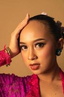 beautiful Balinese woman wearing makeup in a pink dress while posing with exotic hands photo