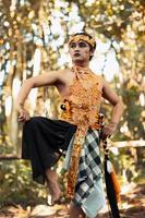 Balinese man raise their feet and dance pose in golden costumes with golden crowns photo