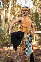 Balinese man raise their feet and dance pose in golden costumes with golden crowns photo