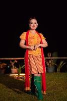 mujer indonesia con un hermoso vestido batik naranja con una bufanda roja y labios rojos en la cara foto