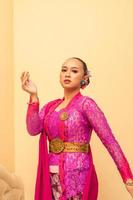 Javanese woman wearing traditional pink dress called kebaya photo