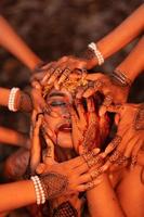 Sad Man Faces covered up by a lot of hands with henna tattoos while wearing a gold crown photo