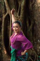 An Indonesian woman bravely poses while raising her hands in a purple dress photo