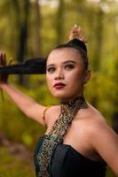 Gorgeous Asian woman in makeup with black hair and red lipstick wearing golden jewelry during the dance performance photo