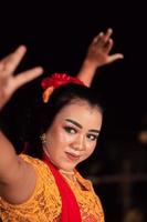 una bailarina tradicional asiática con un vestido naranja con una bufanda roja y maquillaje actuando en el festival de danza foto