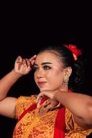 a Sharp gaze from an Indonesian woman with makeup on her face while wearing an orange dress and golden earrings photo